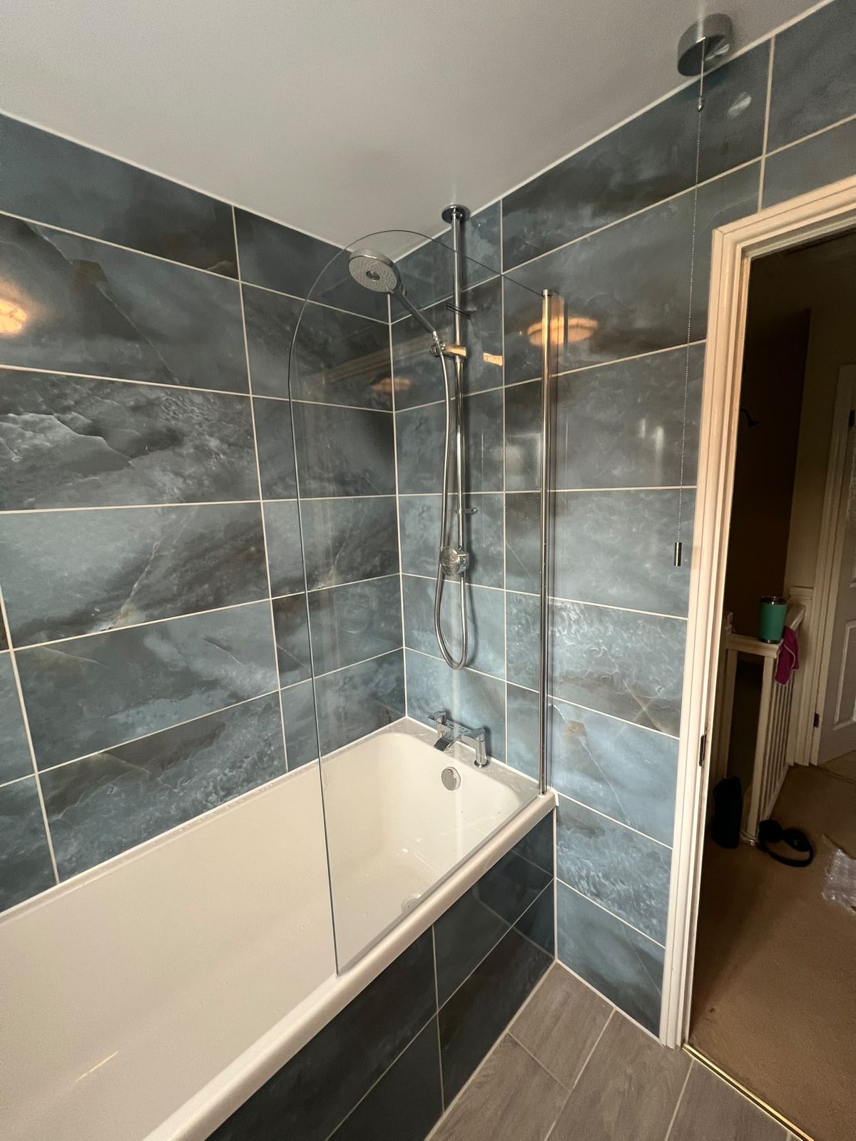 New bath with overhead shower and glass screen in slate-effect tiles