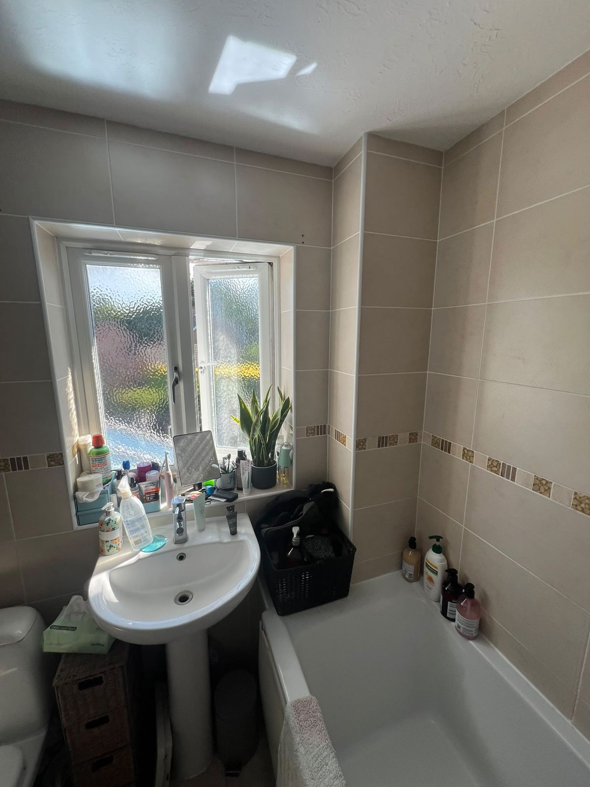 Plain cream-tiled bathroom with pedestal basin before the refit